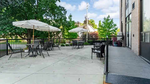 Patio with tables, chairs and white umbrellas beside the building