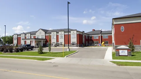 Red and grey building with windows, an entrance canopy and lawns