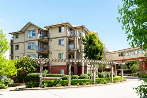Residence exterior with balconies, a pergola, shrubs and a driveway