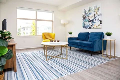 Sitting area with a blue sofa, yellow chair, white coffee table and window