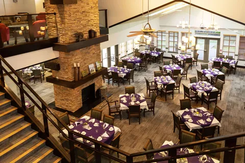 Dining room with set tables, chairs and a stone fireplace viewed from a staircase
