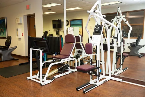 Exercise room with weight machines, a treadmill, bicycle and wall mirrors