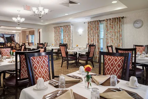 Dining room with set tables and patterned upholstered chairs.