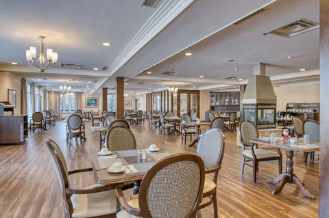 Dining room with set tables, upholstered chairs and chandeliers.
