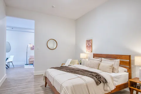 Bedroom with a bed, nightstand and door to an adjoining room.