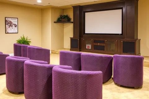 Screening room with purple chairs and a large projection screen.
