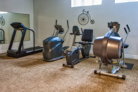Fitness room with treadmills and exercise bikes beside a window.