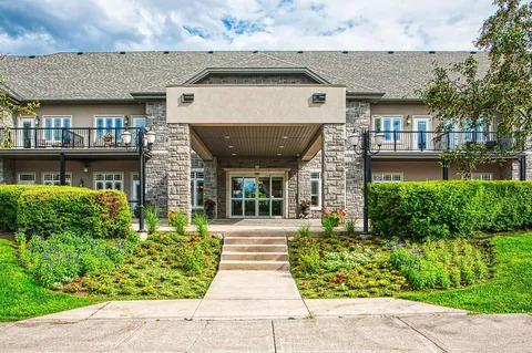 Residence entrance with stone columns beside a landscaped walkway.