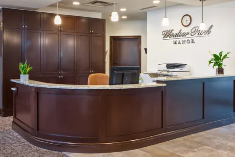 Wood reception counter beside a lobby wall and corridor.
