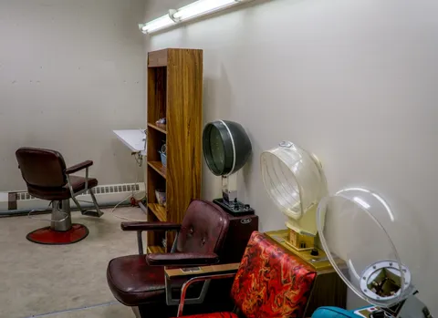 Salon with chairs, hair dryers and wooden shelving