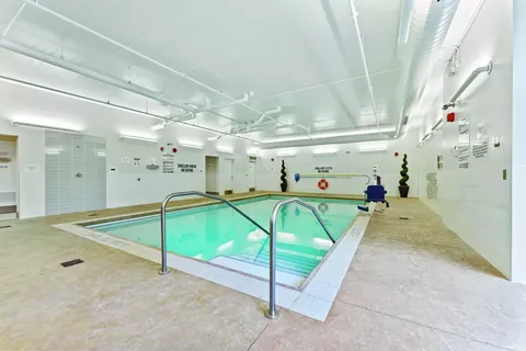 Indoor swimming pool with metal handrails and a tiled deck