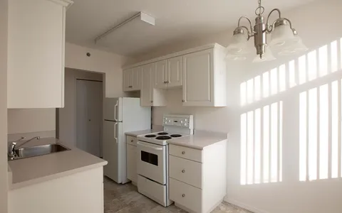Kitchen with white cabinets, a stove, refrigerator, sink and hanging light fixture
