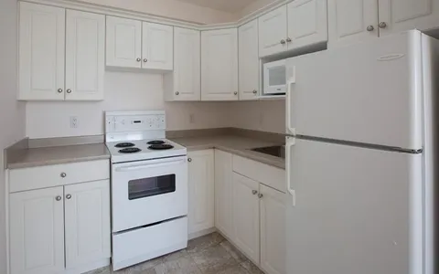 Kitchen with white cabinets, a stove, refrigerator, microwave and sink