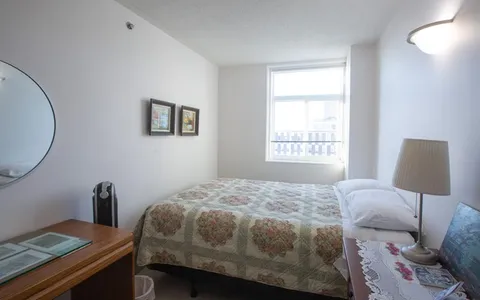 Bedroom with a floral quilt, bedside lamp, wooden desk and framed wall prints