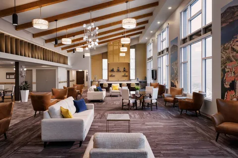 Room with sofas, armchairs, timber ceiling beams and tall windows