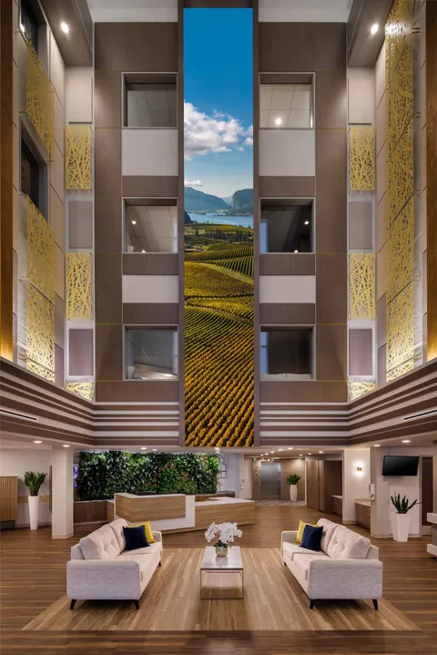Tall atrium with white seats, a coffee table and vertical wall artwork