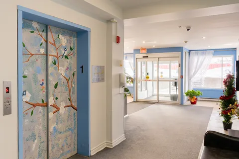 Entrance lobby with glass doors, blue floral elevator doors and a decorated tree