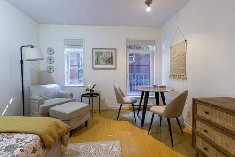 Room with a bed, an armchair, a small dining table and windows
