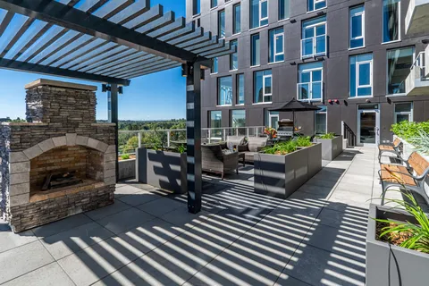 Rooftop terrace with seating, planters and a stone fireplace.