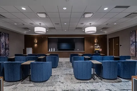 Theatre room with upholstered seating and a wall screen.