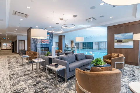 Lounge with sofas and armchairs beside large windows.