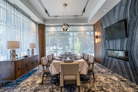Private dining room with a long table beside windows.
