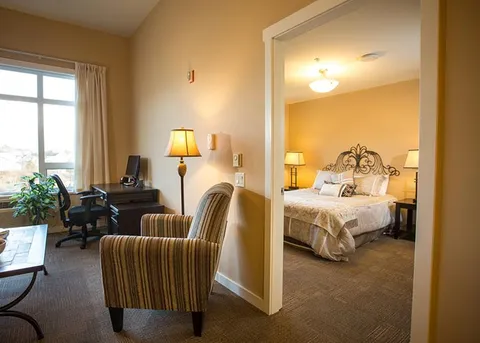 Suite living area beside a bedroom with a double bed.