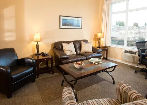 Suite living room with a sofa and armchairs beside windows.