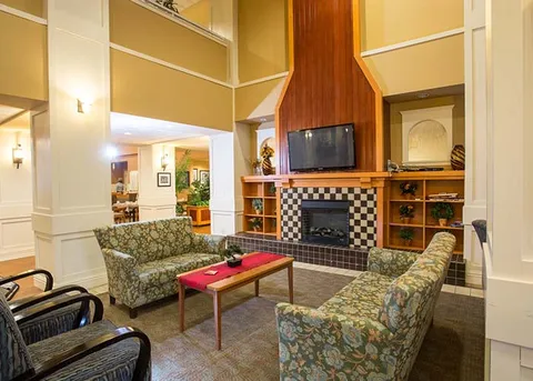 Lounge with patterned sofas, a television and tall shelving.