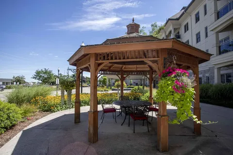 Wooden gazebo with a table, chairs and hanging flowers
