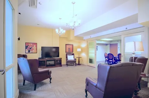 Lounge with armchairs, television and adjoining seating area.