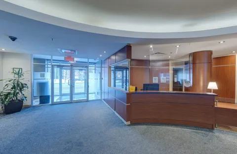 Reception desk beside glass entrance doors and wood-panelled walls