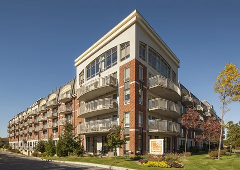 Brick building with rounded balconies, large corner windows and a planted lawn