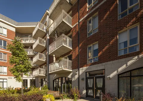 Brick courtyard facades with balconies, glass doors and planted garden beds