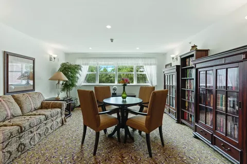Library with glass-front bookcases, a floral sofa and round table