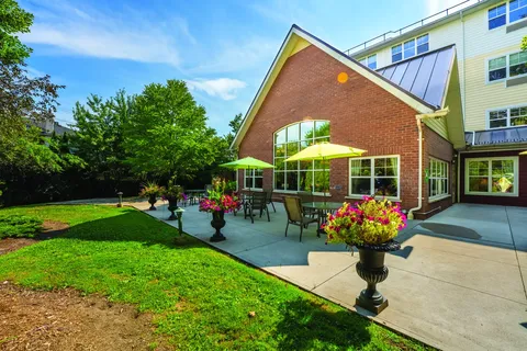 Brick residence wing with large arched windows beside a patio and garden