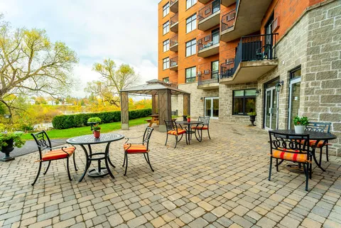 Paved patio with tables, chairs and a gazebo beside the building