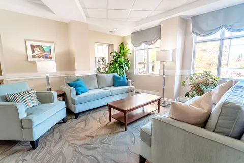 Room with pale blue sofas, armchairs, a coffee table and large windows