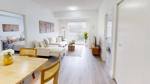 Suite dining and living area with a dining table, sofa and balcony doors.