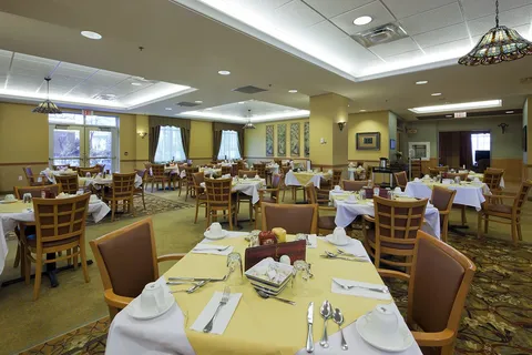 Dining room with set tables, wooden chairs and large windows.