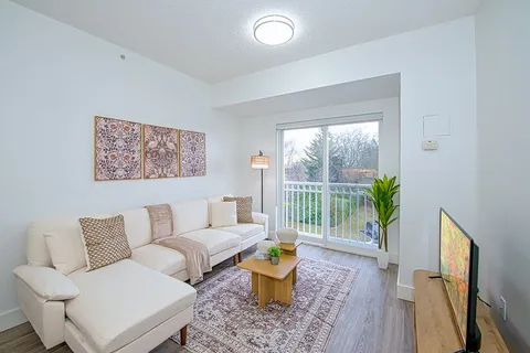 Suite living room with a sofa, television and balcony doors.