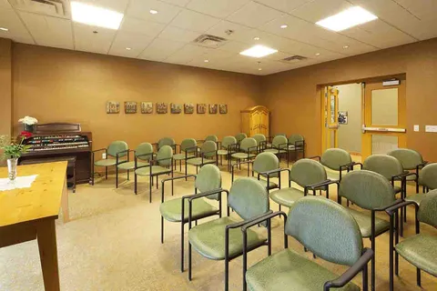 Chapel with rows of chairs and an upright piano.