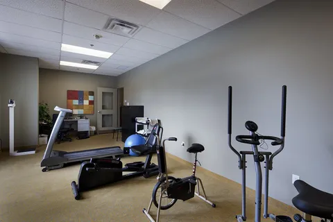 Fitness room with exercise machines and wall mirrors.