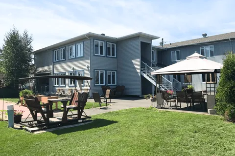 Residence building beside a lawn, patio furniture and a gazebo.