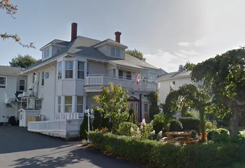 White residence exterior with balconies, driveway and garden.