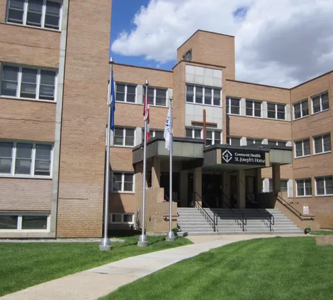 Brick building with an entrance canopy, steps, flagpoles and a lawn