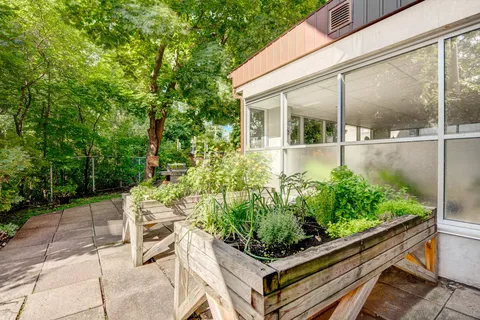 Raised wooden planting beds beside a glazed room and garden path