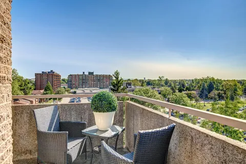 Balcony with woven chairs, a glass table and a potted shrub