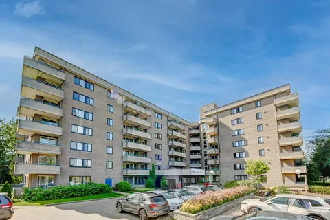 Multi-storey residence with balconies, landscaped beds and a parking area
