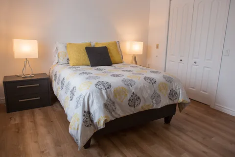 Bedroom with a patterned bedspread, bedside lamps and white wardrobe doors